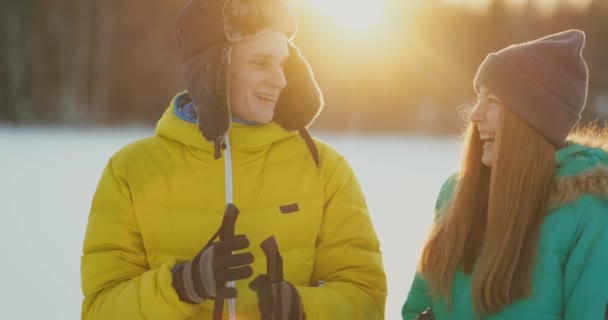 男は、夕暮れ時、冬のスキーで散歩の後、森の中で立っている女性を取り入れています。聖バレンタインの日。愛好家のロマンスと暖かい気持ち。スローモーション - 映像、動画