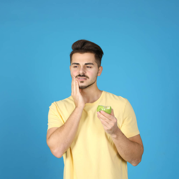 Emotional young man with sensitive teeth and ice cream on color background. Space for text - Φωτογραφία, εικόνα
