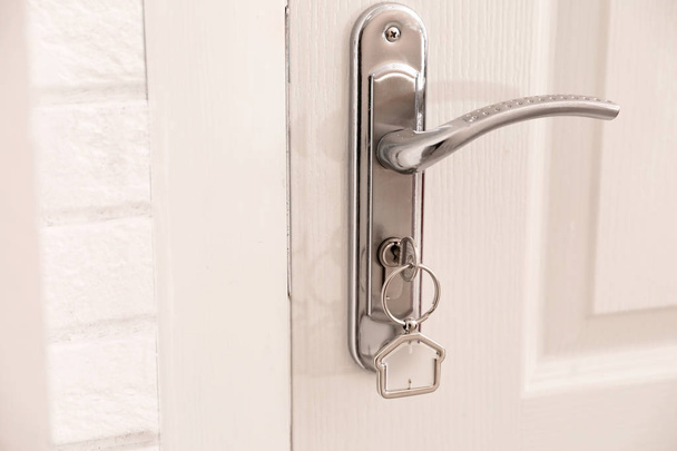 Key with house-shaped trinket in door lock, closeup. Space for text - Zdjęcie, obraz
