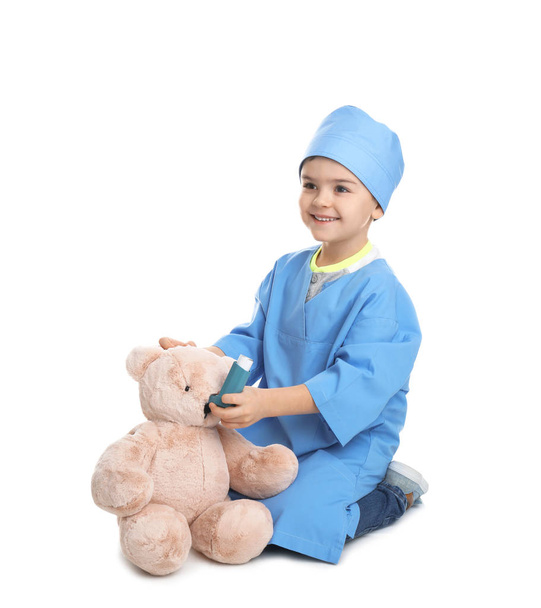 Cute child playing doctor with stuffed toy on white background - Foto, immagini