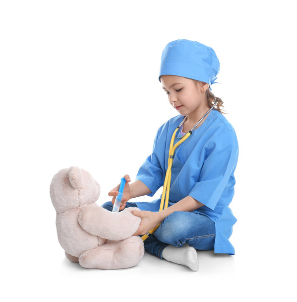 Cute child playing doctor with stuffed toy on white background - Фото, зображення