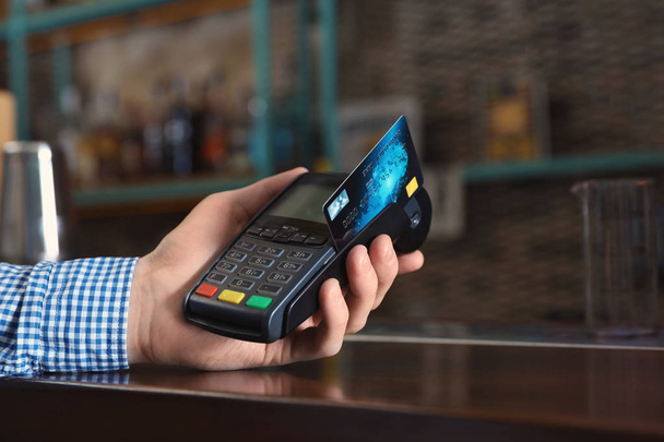 Hombre que utiliza la máquina de tarjeta de crédito para el pago sin efectivo en la cafetería, primer plano. Espacio para texto
 - Foto, imagen