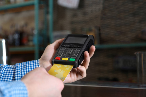Hombre que utiliza la máquina de tarjeta de crédito para el pago sin efectivo en la cafetería, primer plano. Espacio para texto
 - Foto, Imagen