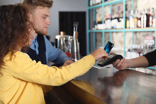 Clientes que utilizan la máquina de tarjeta de crédito para el pago sin efectivo en la cafetería
 - Foto, Imagen