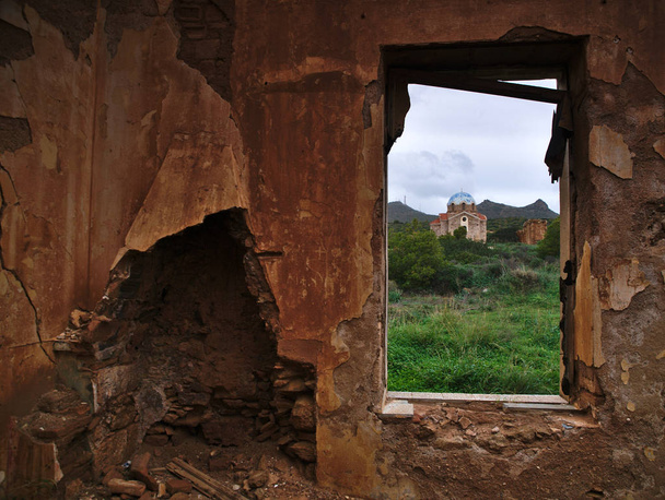 Attica, Greece.Abandoned Kilisesi, Agios Ioannis Prodromos tarafından bir pencere yıkık bir evde Sounio, eski Ortodoks Kilisesi bulutlu gökyüzü altında çerçeveli. - Fotoğraf, Görsel