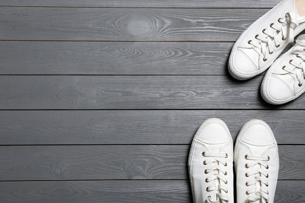 White sneakers and space for text on wooden background, top view. Stylish shoes - Zdjęcie, obraz