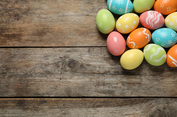 Muitos coloridos pintados ovos de Páscoa em fundo de madeira, vista superior. Espaço para texto
 - Foto, Imagem