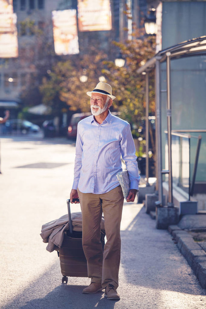 Happy Senior tourist man with suitcase in city. - Fotó, kép