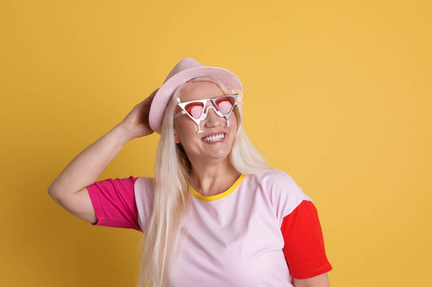 Portrait of mature woman in hipster outfit on color background - Fotó, kép