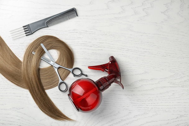 Flat lay composition with hair lock and tools on wooden background. Space for text - Foto, Bild