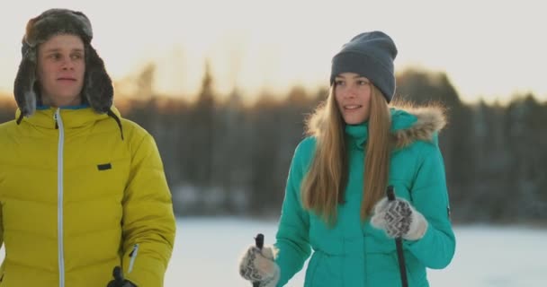 Bir adam ormanda kış bir arkadaşıyla yürüyüş sonra kayaklar üzerinde günbatımında duran bir kadın kucaklar. St Sevgililer günü. Aşıkların Romance ve sıcak duygular. Ağır çekim - Video, Çekim