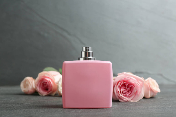 Bottle of perfume with beautiful roses on table - Fotografie, Obrázek