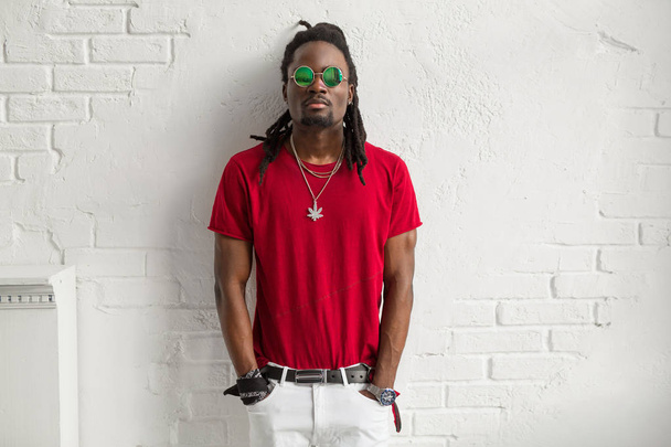 stylish man in red t-shirt with glasses and dreadlocks on a white background - Foto, imagen