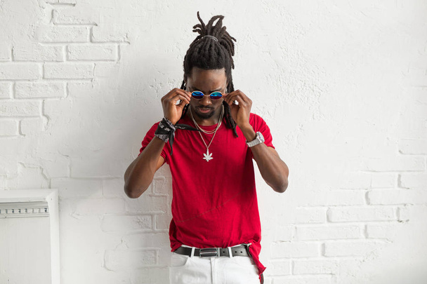 stylish man in red t-shirt with glasses and dreadlocks on a white background - Photo, image