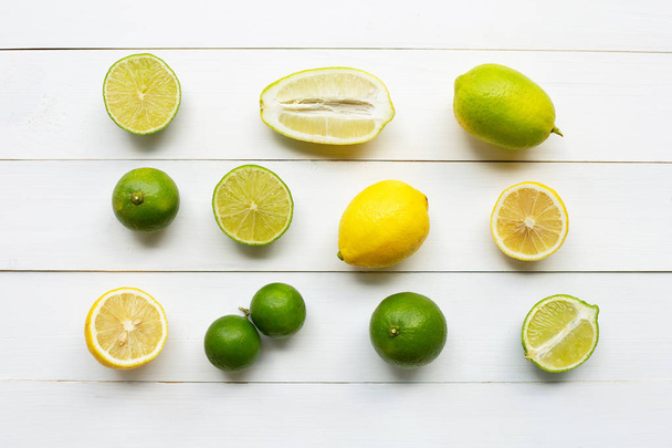 Rijpe citroenen en limoenen op wit houten. - Foto, afbeelding