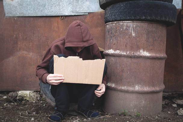 Un senzatetto con in mano un cartone bianco
. - Foto, immagini