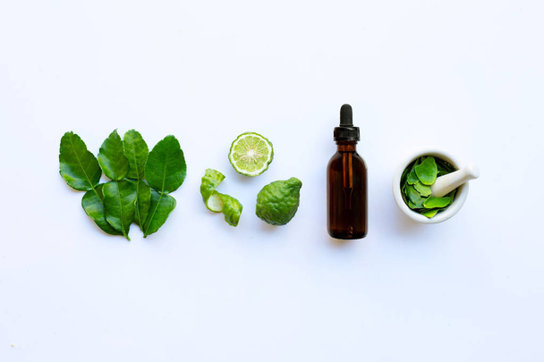 Bottle of essential oil and  fresh kaffir lime or bergamot fruit - Fotó, kép