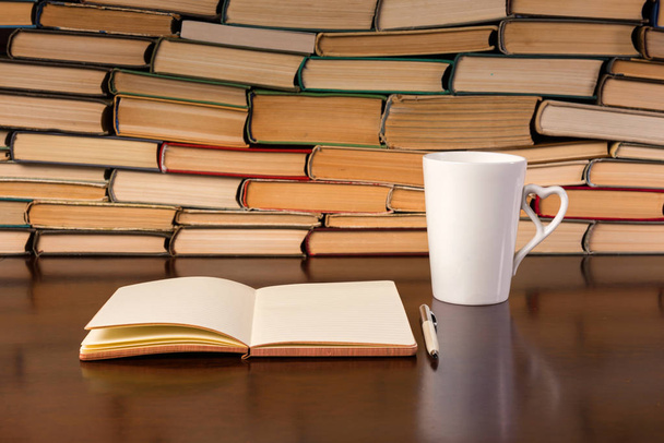 cup, notebook and many books on a wooden table - 写真・画像
