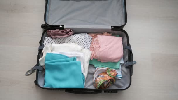 Een vrouw is het inpakken van een koffer. meisje zet dingen samen voor reizen. - Video