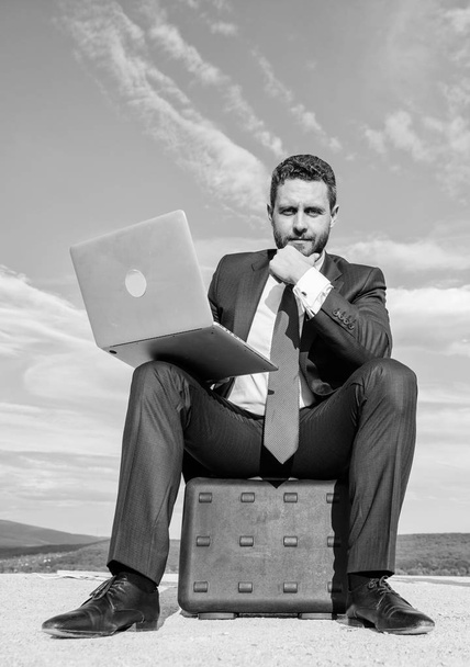 Laptop indispensable attribute modern businessman. Modern technologies portable device opportunity work worldwide. Business on fresh air. Businessman with laptop sit briefcase blue sky background - Foto, Bild