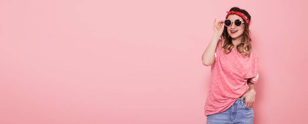 Mooi jong meisje in roze t-shirt op roze achtergrond - Foto, afbeelding