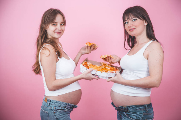beslenme kavramı, hamile kadınlar pembe bir arka plan üzerinde pizza yemek - Fotoğraf, Görsel