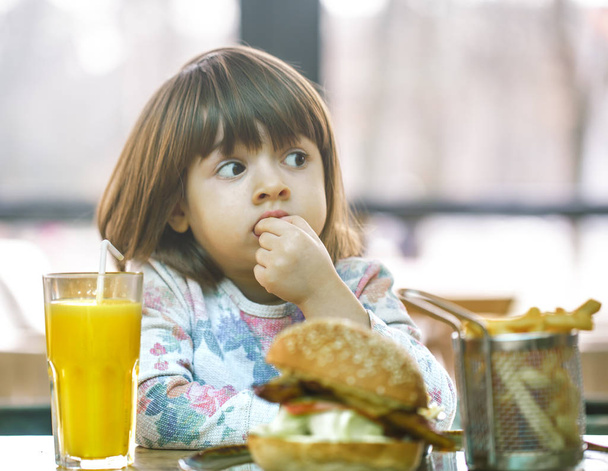 Little girl eats in a fast food cafe - Photo, Image