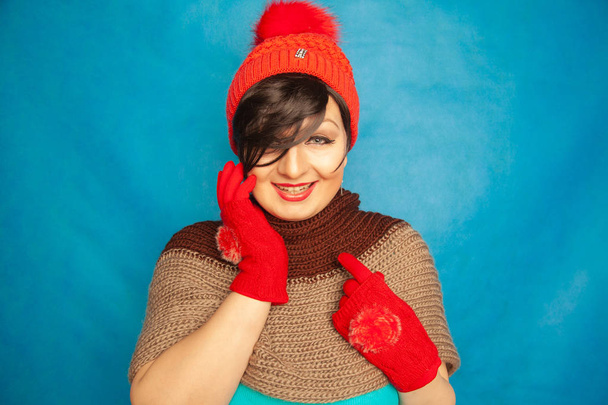menina morena bonita vestindo moda vermelho tricotado inverno gat e quente belas luvas no estúdio azul fundo sólido
 - Foto, Imagem