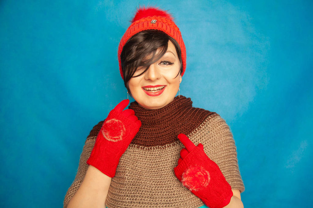 jolie fille brune portant la mode rouge tricoté gat d'hiver et chaud de beaux gants sur fond bleu studio solide
 - Photo, image