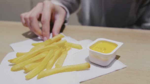 Woman eating French fries with cheese sauce in cafe. Close-up hands. - Video, Çekim