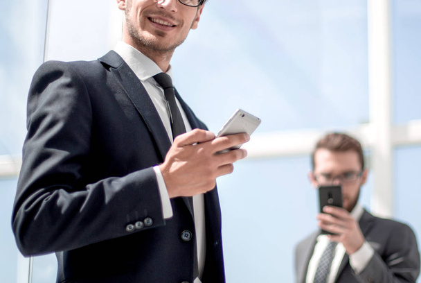 modern businessman with a smartphone on background office - Фото, зображення