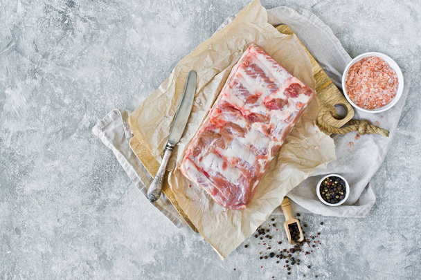Raw pork ribs on a wooden chopping Board. Gray background, top view, space for text - Fotó, kép