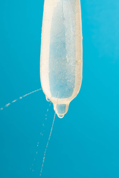 Water is gelekt uit een condoom vol met gaten. Controle test voor de kwaliteit. - Foto, afbeelding