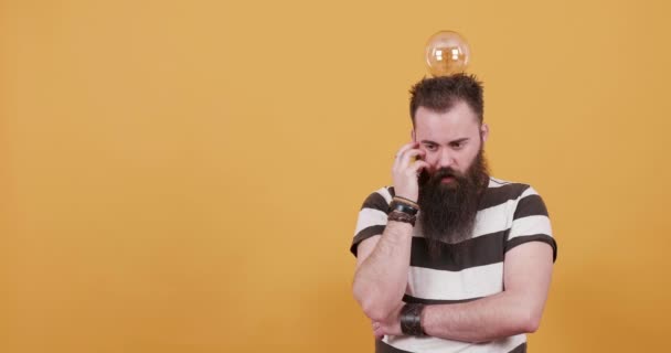 Bearded young man with a bulb over his head getting an idea - Felvétel, videó