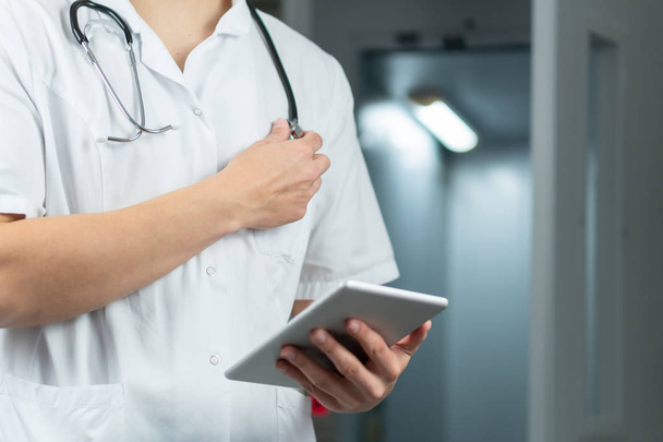 Яскраво крупним планом чоловічий лікар в уніформі тримає стетоскоп і використовує комп'ютерний планшет в лікарні. Медична концепція з копіювальним простором
 - Фото, зображення