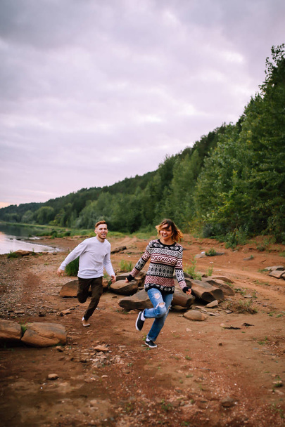Young couple having fun and running along the river - Фото, изображение