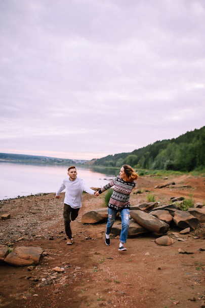 Young couple having fun and running along the river - Fotoğraf, Görsel