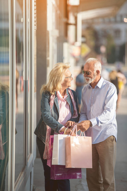Happy mature couple walking with their shopping purchases on a sunny day - Foto, Imagem