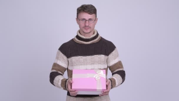 Happy handsome bearded man smiling while giving gift box - Video