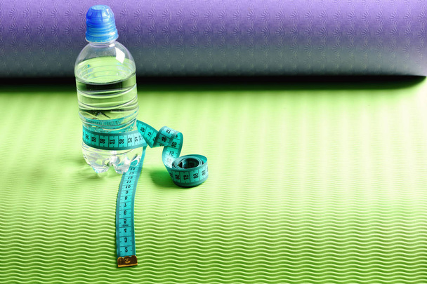 Water bottle and flexible ruler in blue on yoga mat - Фото, изображение