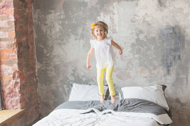 Happy child girl having fun jumping on a bed - Foto, imagen