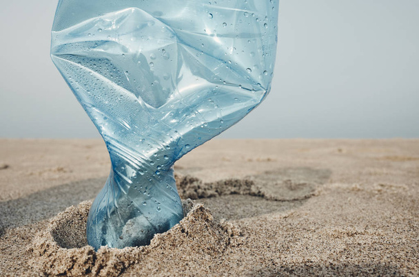 Plastic bottle stuck in sand on a beach - 写真・画像