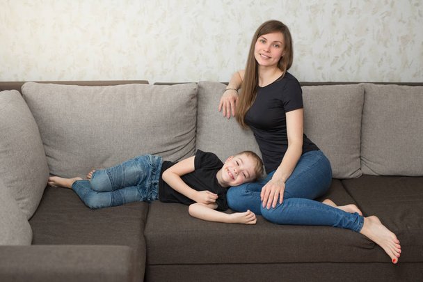 beautiful young mother with her son on the couch in the home interior - 写真・画像