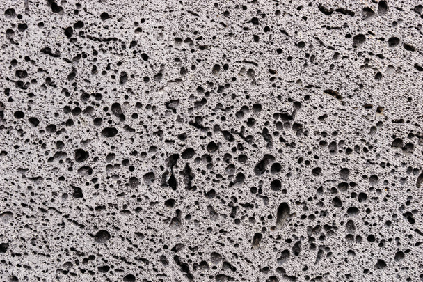 Vértes szürke porózus szerkezetű kőfal. Kő háttér - Fotó, kép