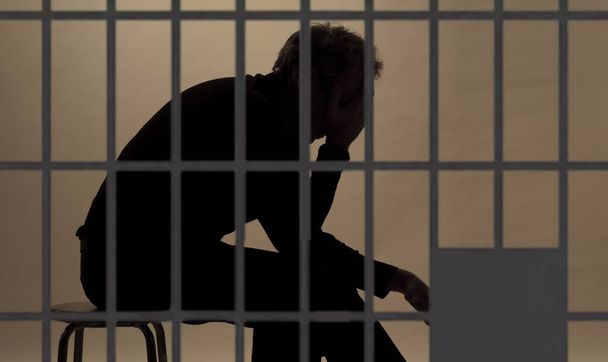 κρατούμενος στη φυλακή, σιλουέτα πέρα από τα μπαρ του κυττάρου - Φωτογραφία, εικόνα