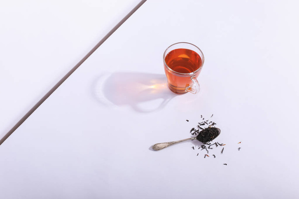 Glass cup with tea and brew, on a white background. The harsh sh - Fotoğraf, Görsel