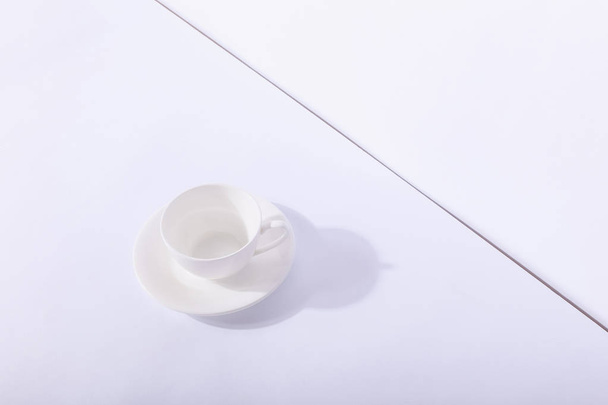 Empty ceramic cup on saucer, on white background. Hard shadow fr - Valokuva, kuva