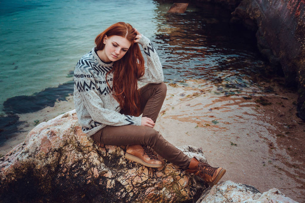 海沿いを歩いて自然の美を楽しむそばかすと赤毛の美しい若い女性 - 写真・画像