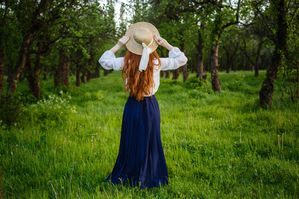 Portret lato, piękny piegowaty młoda kobieta nosi kapelusz słomkowy. Dziewczyna w spring apple garden - Zdjęcie, obraz