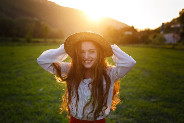 Retrato de verão, bela jovem sardenta usando chapéu de palha ao pôr do sol no campo
 - Foto, Imagem